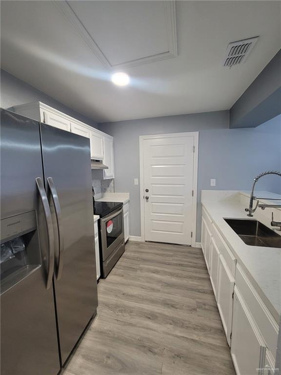 kitchen with white cabinetry, appliances with stainless steel finishes, light hardwood / wood-style floors, and sink