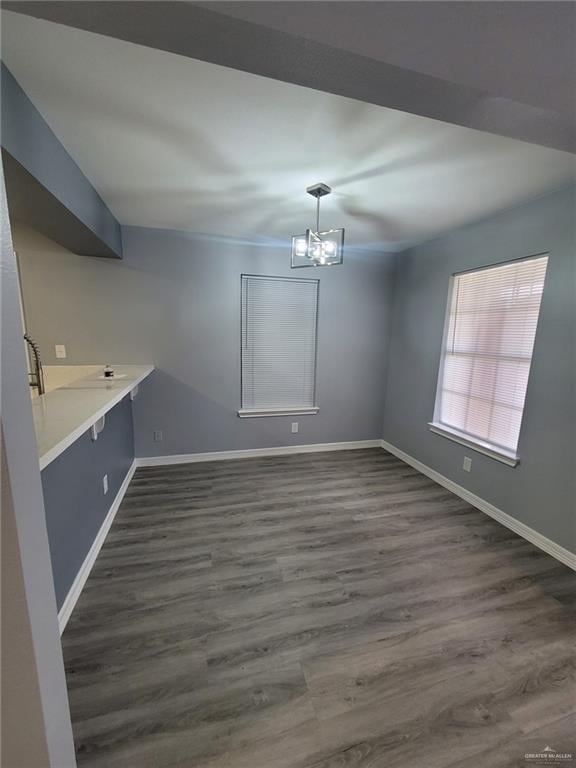 unfurnished dining area with dark wood-type flooring and an inviting chandelier