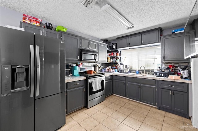 1729 W Jefferson St, Weslaco, TX 78599 - kitchen featuring appliances with stainless steel finishes, a textured ceiling, light countertops, light tile patterned flooring, and open shelves