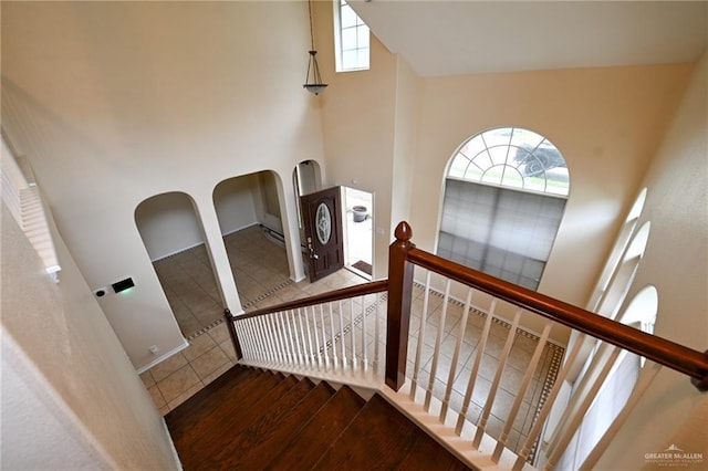 stairs with hardwood / wood-style floors and a high ceiling