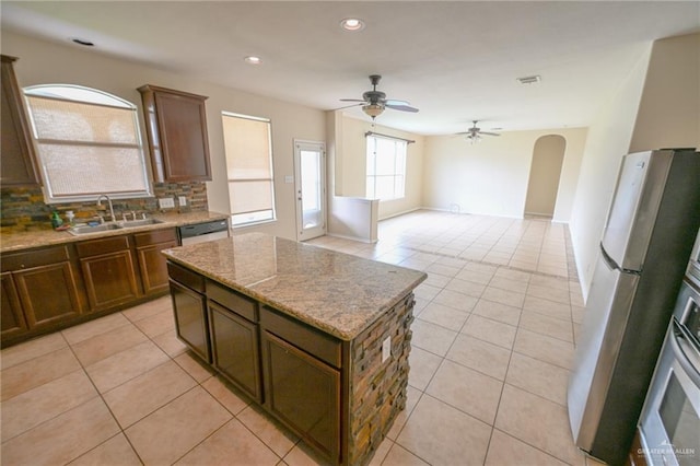 kitchen with a center island, sink, ceiling fan, decorative backsplash, and appliances with stainless steel finishes