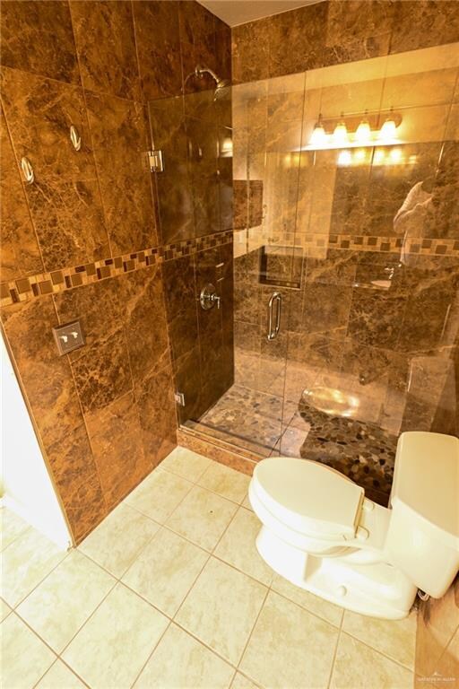 bathroom with tile patterned floors, toilet, and walk in shower