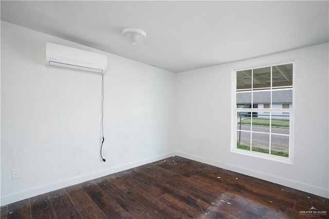 unfurnished room with a wall mounted air conditioner, dark wood finished floors, and baseboards