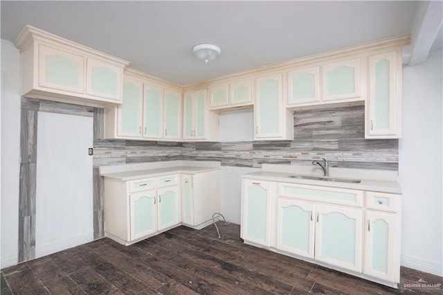 kitchen with white cabinets, dark wood-style floors, backsplash, light countertops, and a sink