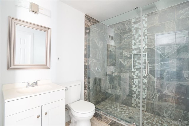 bathroom with a stall shower, vanity, and toilet