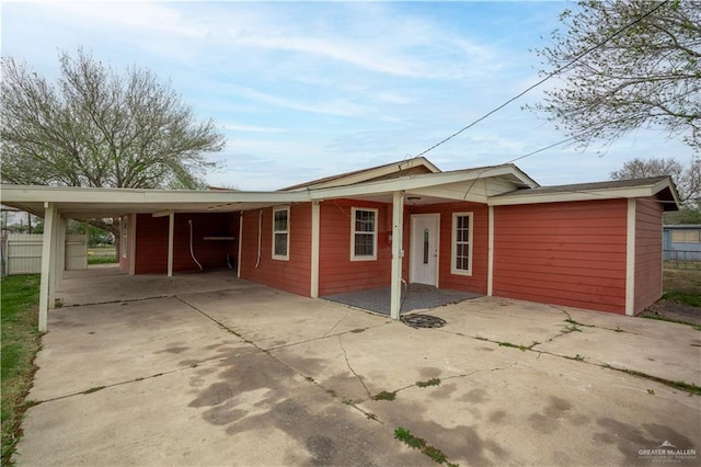 exterior space featuring concrete driveway, an attached carport, and fence