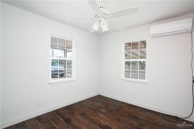 spare room with a wall unit AC, baseboards, dark wood finished floors, and a ceiling fan