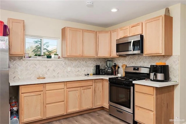 kitchen with light brown cabinetry, backsplash, appliances with stainless steel finishes, and light hardwood / wood-style flooring