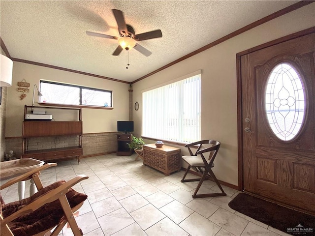 tiled entrance foyer featuring crown molding, a healthy amount of sunlight, and a textured ceiling