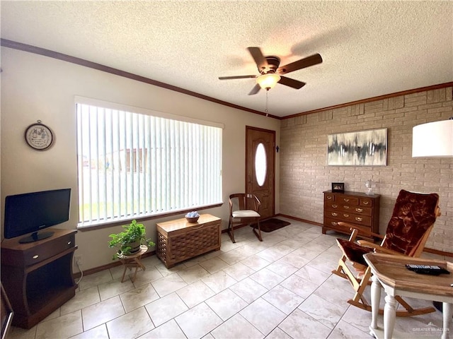 sitting room featuring a textured ceiling, ornamental molding, ceiling fan, and brick wall