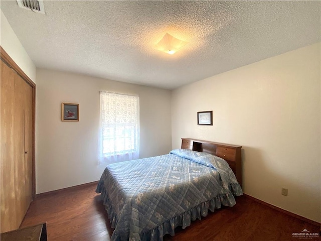 bedroom featuring dark hardwood / wood-style flooring, a closet, and a textured ceiling