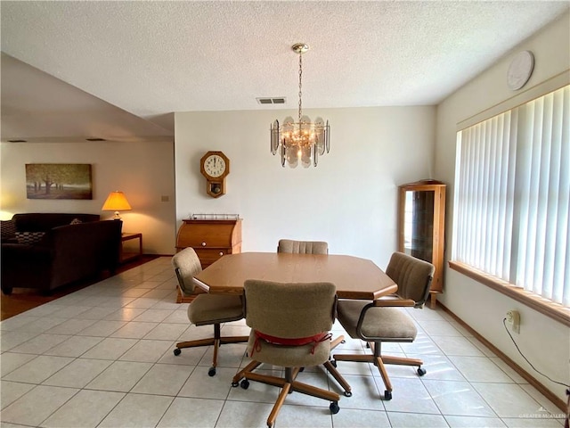 dining area featuring light tile patterned flooring, an inviting chandelier, and a textured ceiling