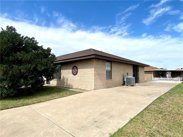 view of side of property featuring central AC unit and a lawn