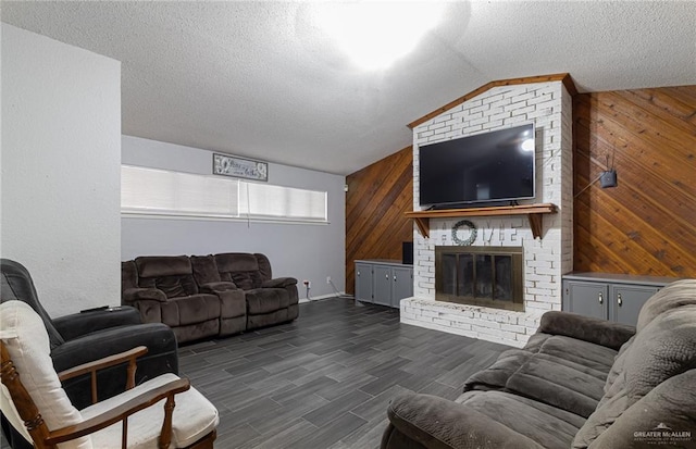 living room featuring dark hardwood / wood-style flooring, a textured ceiling, vaulted ceiling, a fireplace, and wood walls