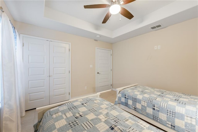 bedroom featuring a closet, a raised ceiling, and ceiling fan