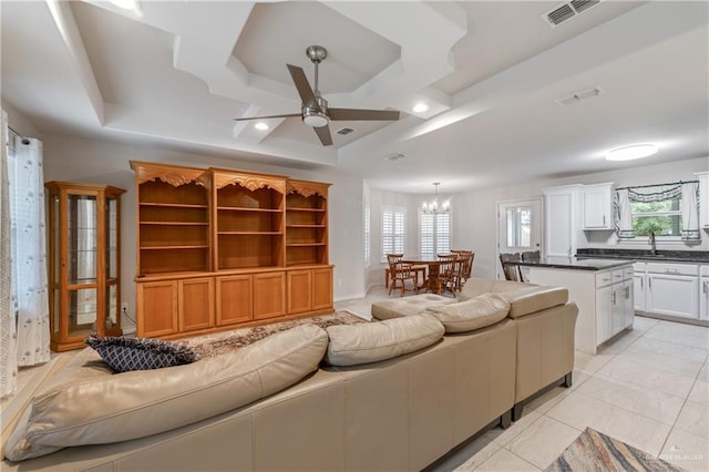 tiled living room with ceiling fan with notable chandelier, coffered ceiling, and a wealth of natural light