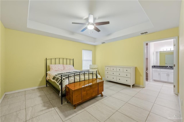 tiled bedroom with ceiling fan, ensuite bathroom, a raised ceiling, and sink