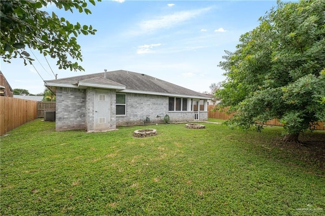 rear view of house with a yard, cooling unit, and an outdoor fire pit