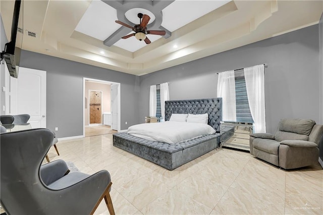 bedroom featuring a tray ceiling, ceiling fan, and ensuite bathroom