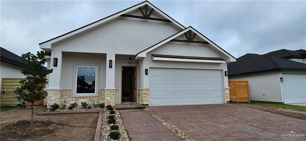 view of front of house with driveway, stucco siding, a garage, and fence