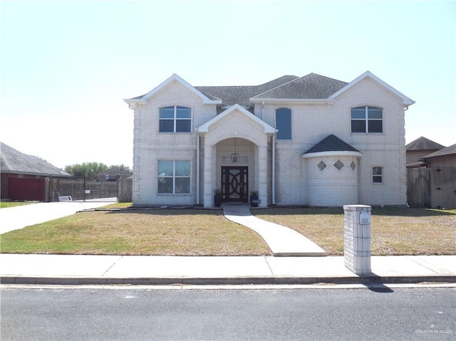 traditional home with brick siding, a front yard, and fence