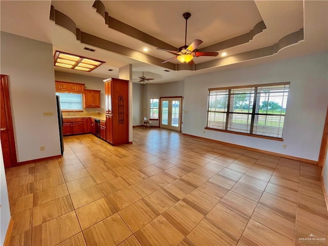 unfurnished living room featuring french doors, a tray ceiling, ceiling fan, and light tile patterned flooring