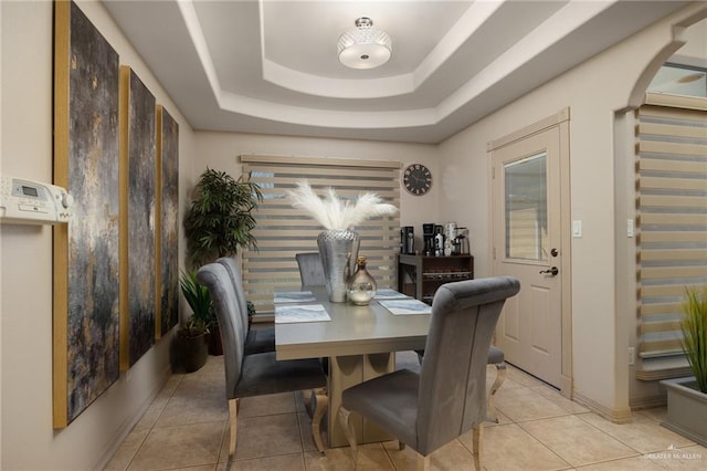 tiled dining area featuring a tray ceiling