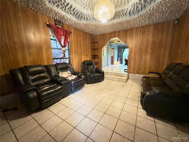 living room featuring tile patterned flooring, a chandelier, and wood walls