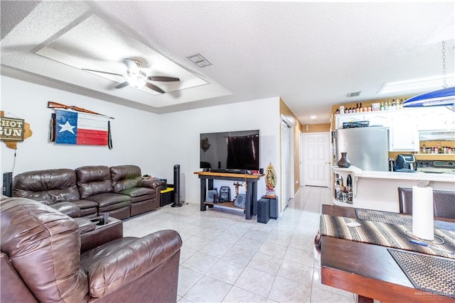 living room featuring ceiling fan, light tile patterned floors, and a textured ceiling