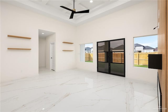 empty room featuring ceiling fan, a healthy amount of sunlight, and a high ceiling