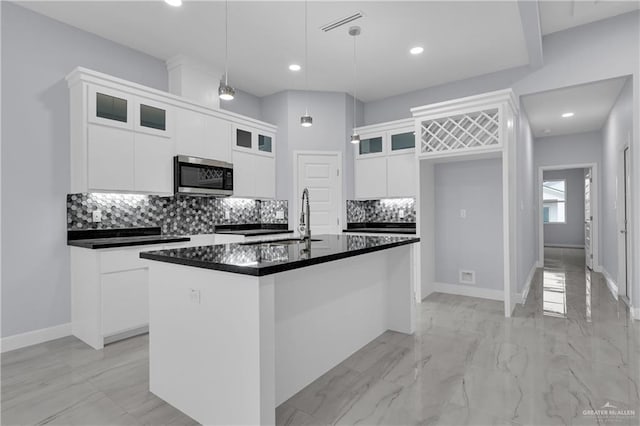 kitchen with sink, decorative light fixtures, decorative backsplash, a center island with sink, and white cabinets