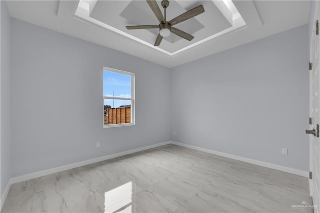 empty room with ceiling fan and a raised ceiling