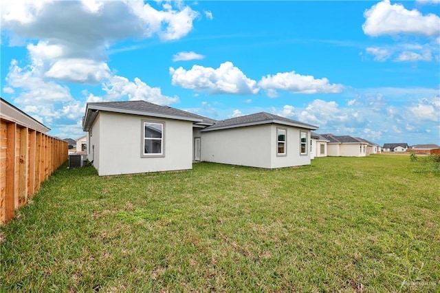 rear view of property with central AC unit and a yard