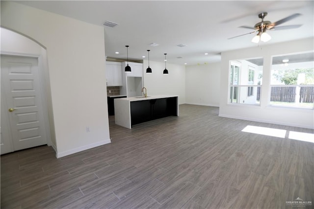 unfurnished living room with ceiling fan, sink, and dark wood-type flooring