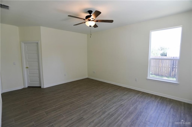 empty room featuring a wealth of natural light, ceiling fan, and dark wood-type flooring