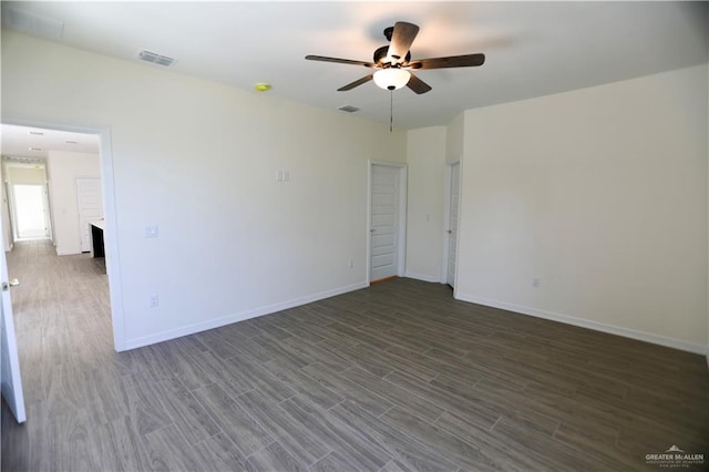 spare room featuring ceiling fan, a fireplace, and dark wood-type flooring