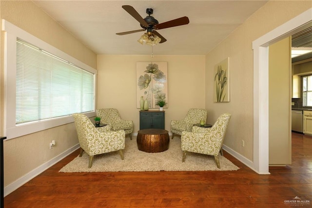 sitting room featuring dark wood-type flooring, ceiling fan, and a healthy amount of sunlight