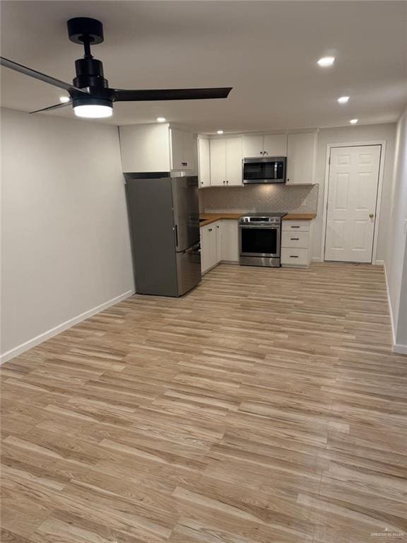 kitchen with appliances with stainless steel finishes, light wood-type flooring, white cabinetry, and decorative backsplash