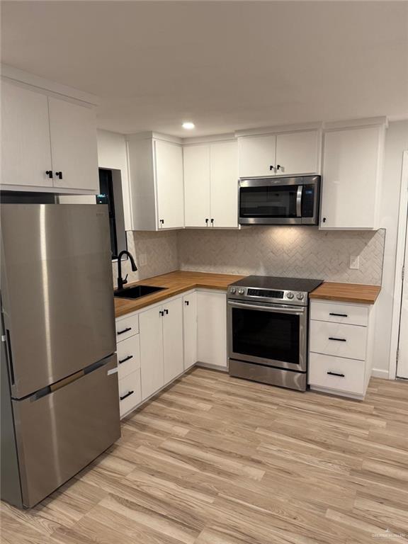 kitchen with white cabinetry, appliances with stainless steel finishes, wooden counters, and a sink