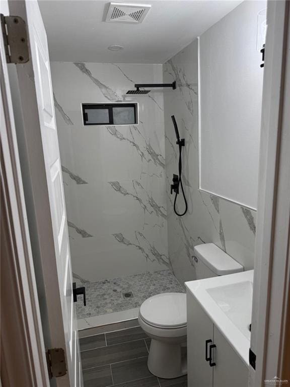 full bathroom with toilet, a marble finish shower, visible vents, and vanity