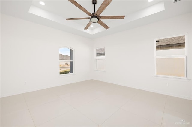 unfurnished room with a tray ceiling, tile patterned floors, and ceiling fan