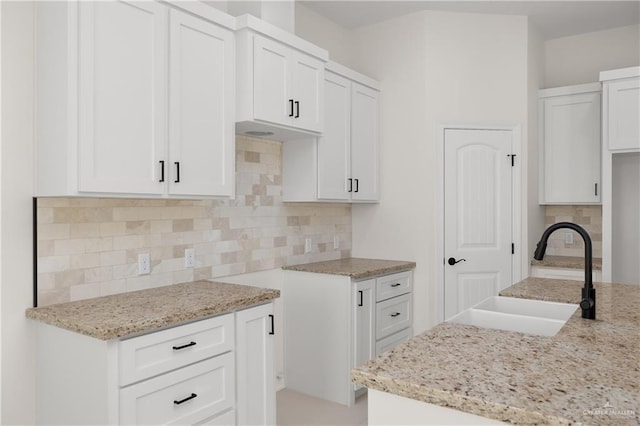 kitchen featuring decorative backsplash, light stone counters, white cabinetry, and sink