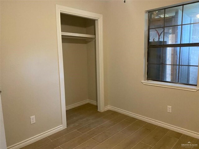 unfurnished bedroom featuring a closet and dark wood-type flooring