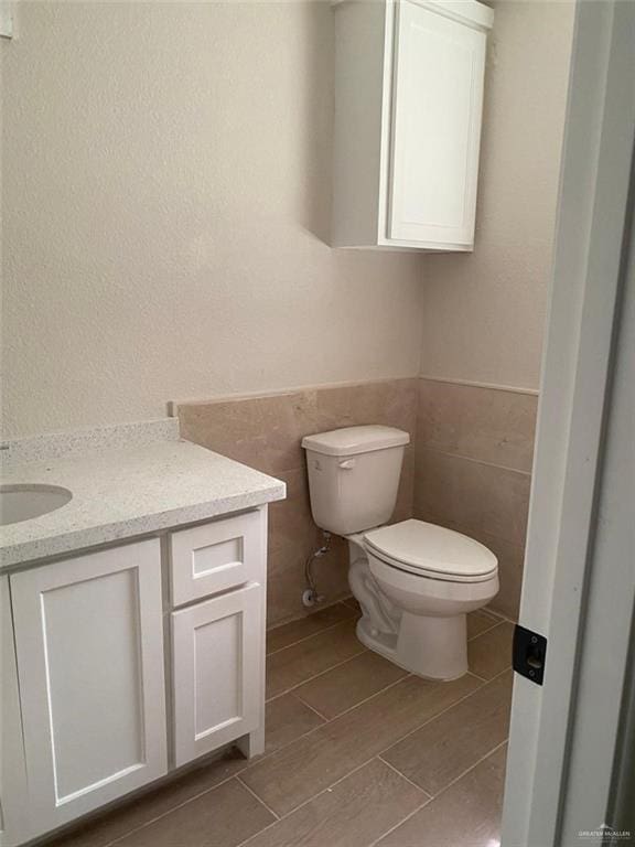 bathroom featuring vanity, toilet, and tile walls