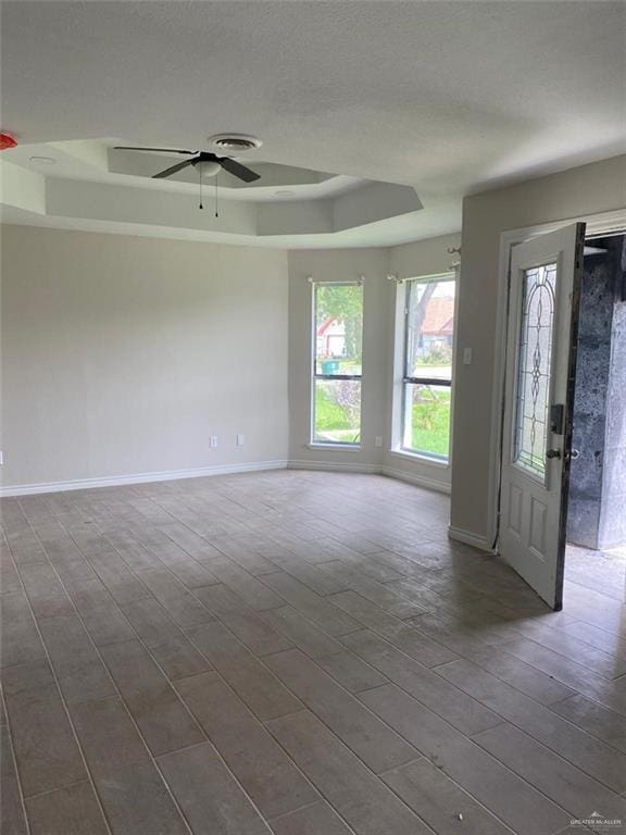 unfurnished room with a tray ceiling, ceiling fan, and hardwood / wood-style flooring