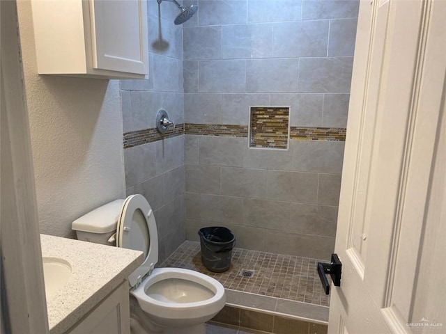 bathroom featuring vanity, toilet, and a tile shower