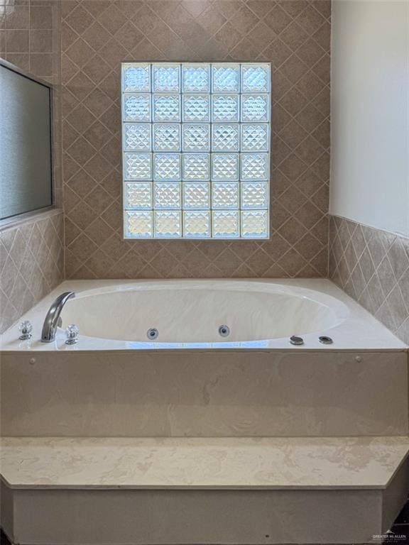 full bathroom featuring a whirlpool tub and tile walls