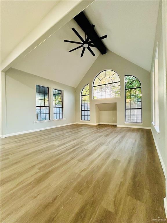 915 Durango St, Mission, TX 78572 - unfurnished living room with high vaulted ceiling, a ceiling fan, wood finished floors, baseboards, and beam ceiling