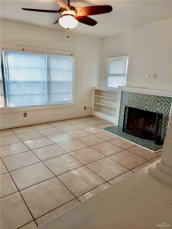 unfurnished living room with a tile fireplace, a wealth of natural light, and light tile patterned floors