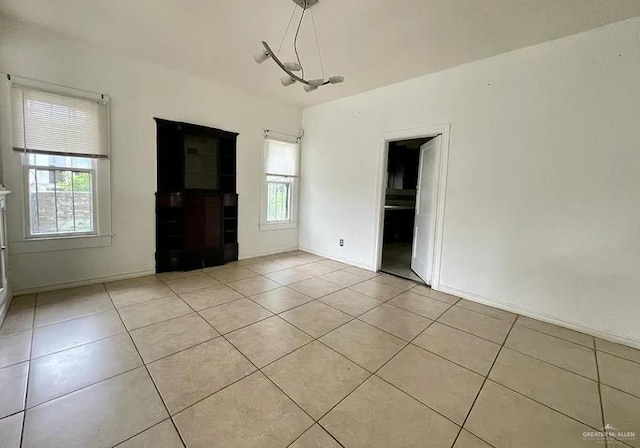 unfurnished room with light tile patterned floors and an inviting chandelier